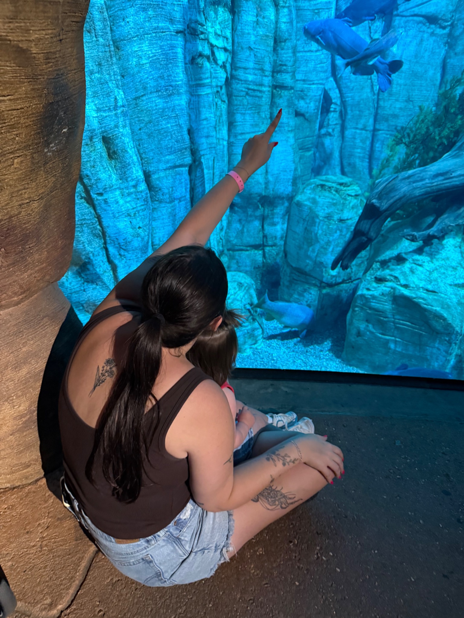 Emily and her daughter at an aquarium, with her daughter's face turned away